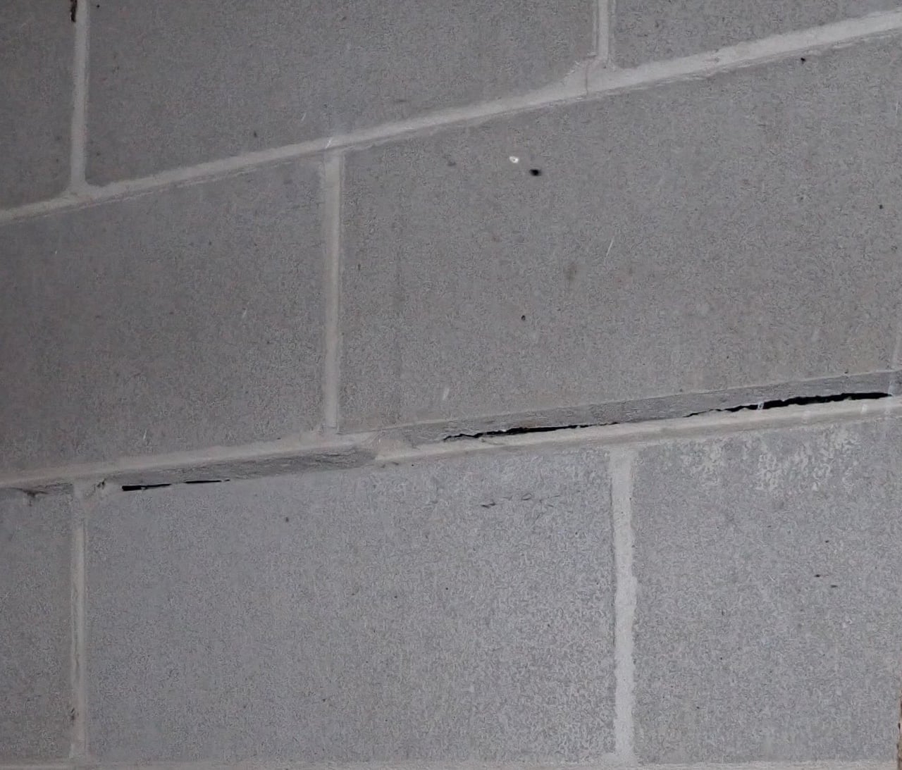 Close detail of displaced concrete-block courses at a horizontal mortar-joint separation