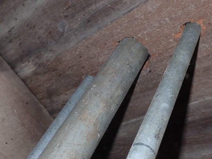 Close-up of two aged gray galvanized steel water supply pipes