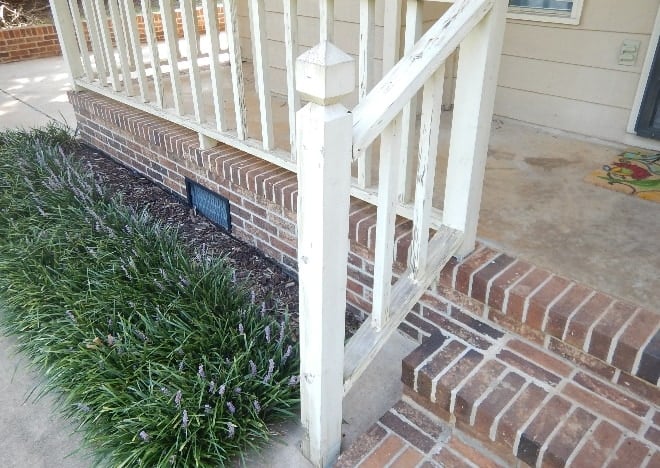 Front porch brick steps with a white wooden stair railing that appears weakly connected at the bottom newel post