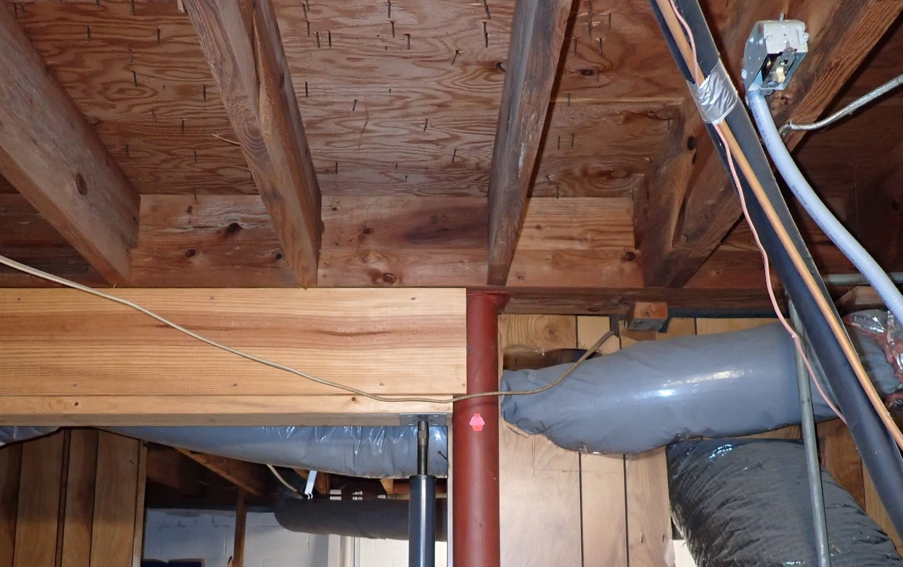 Basement multi-ply girder supported by a metal column and an adjustable jack post